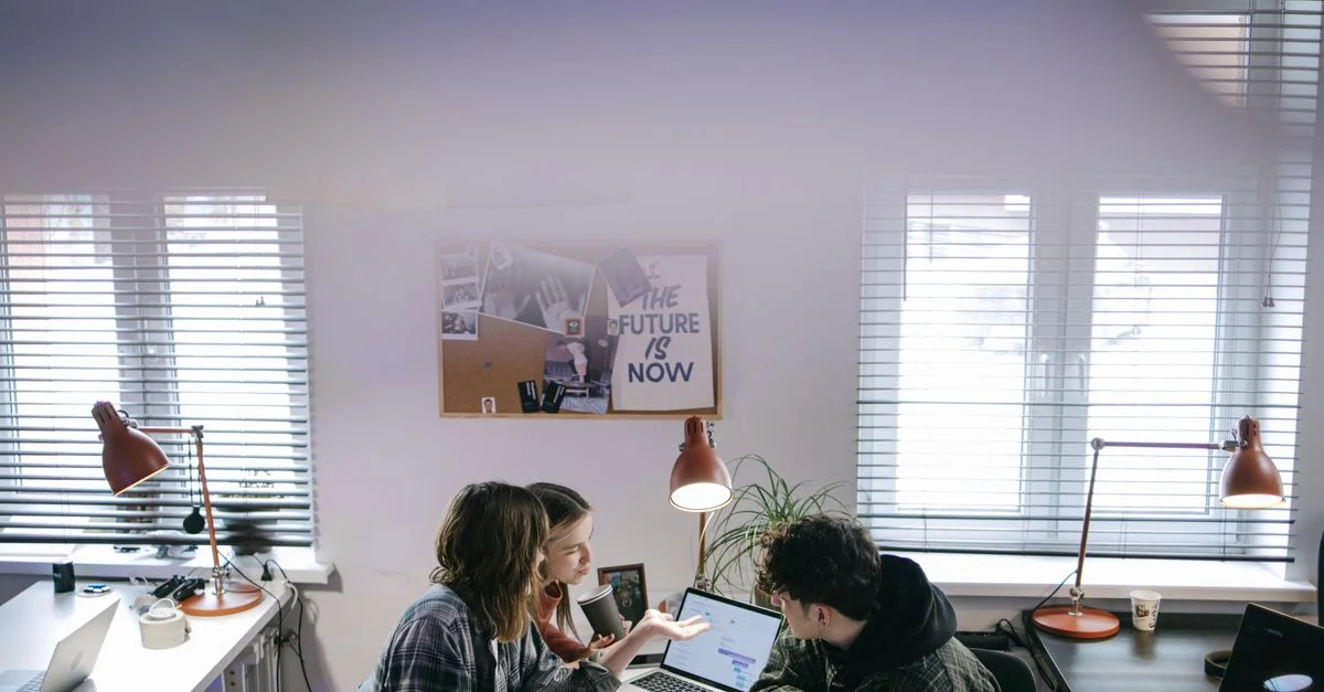 Un groupe de personnes discutant d'idées autour d'ordinateurs portables dans un espace de bureau moderne et lumineux.