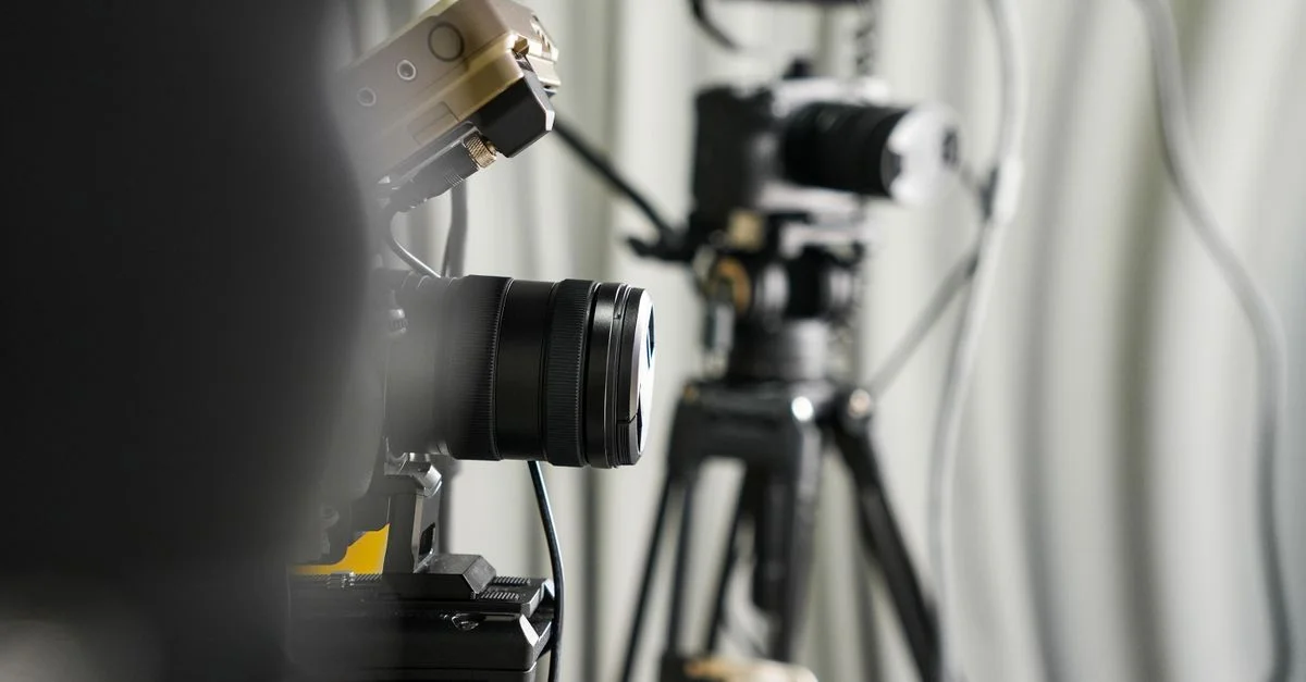 Gros plan sur des caméras vidéo professionnelles sur trépieds dans un studio.