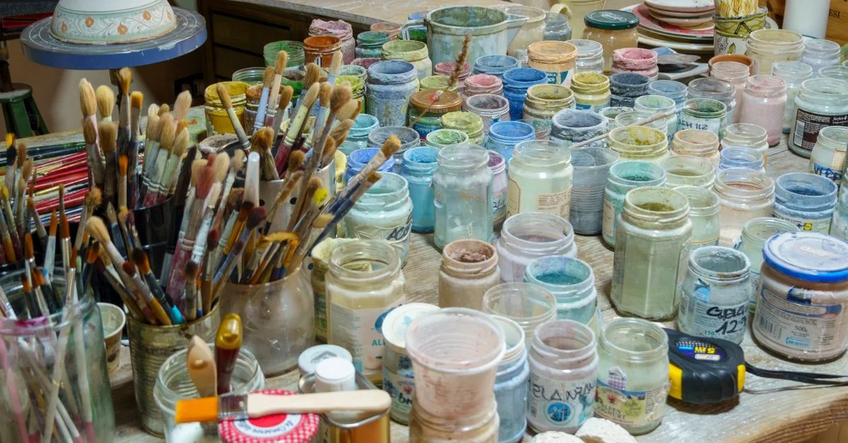 Un assortiment de peintures colorées et de pinceaux disposés sur une table dans le studio d'un artiste.