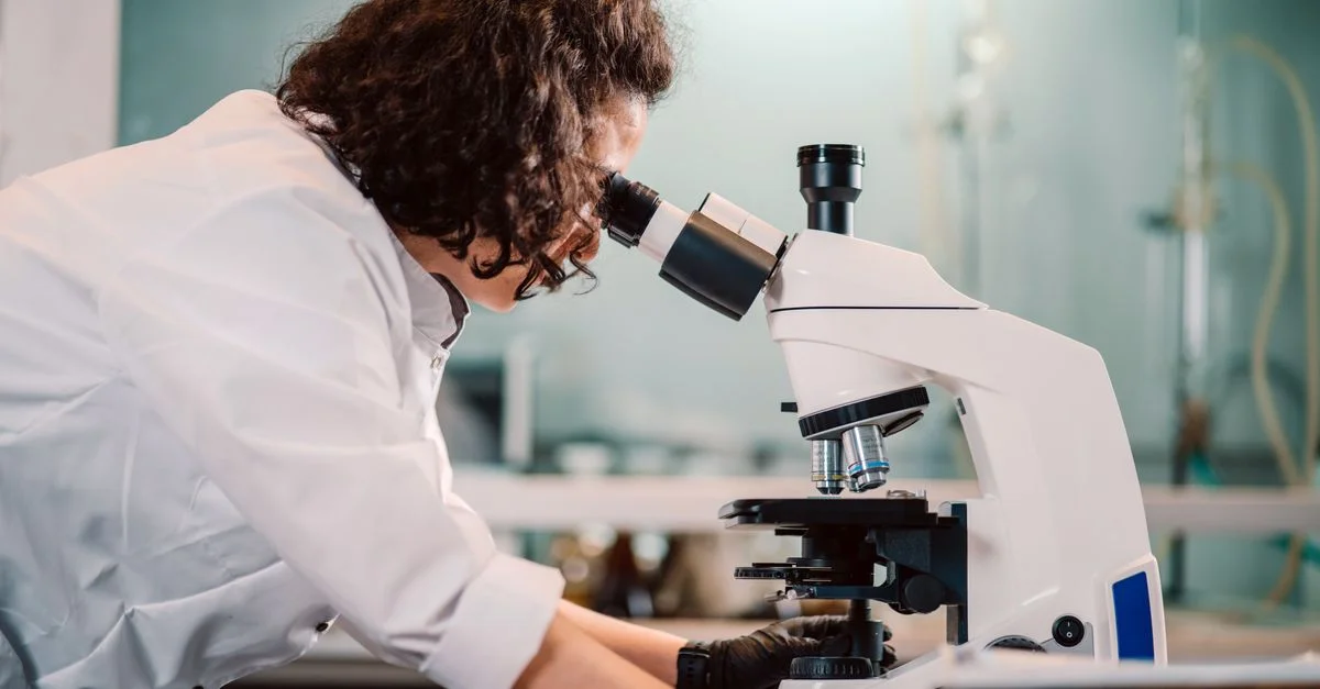 Une femme scientifique utilisant un microscope dans un environnement de laboratoire.